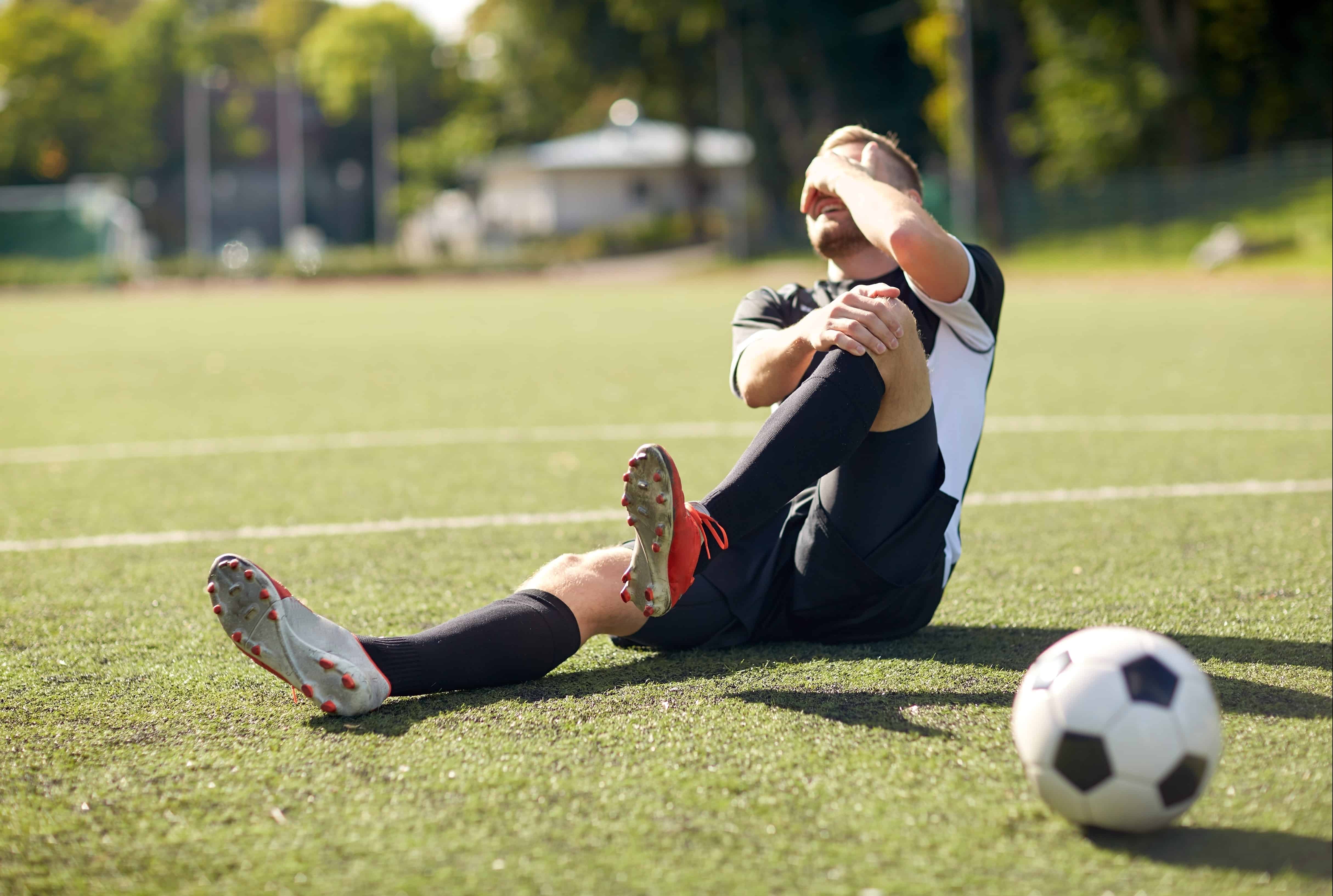 Male soccer player holding their head in pain