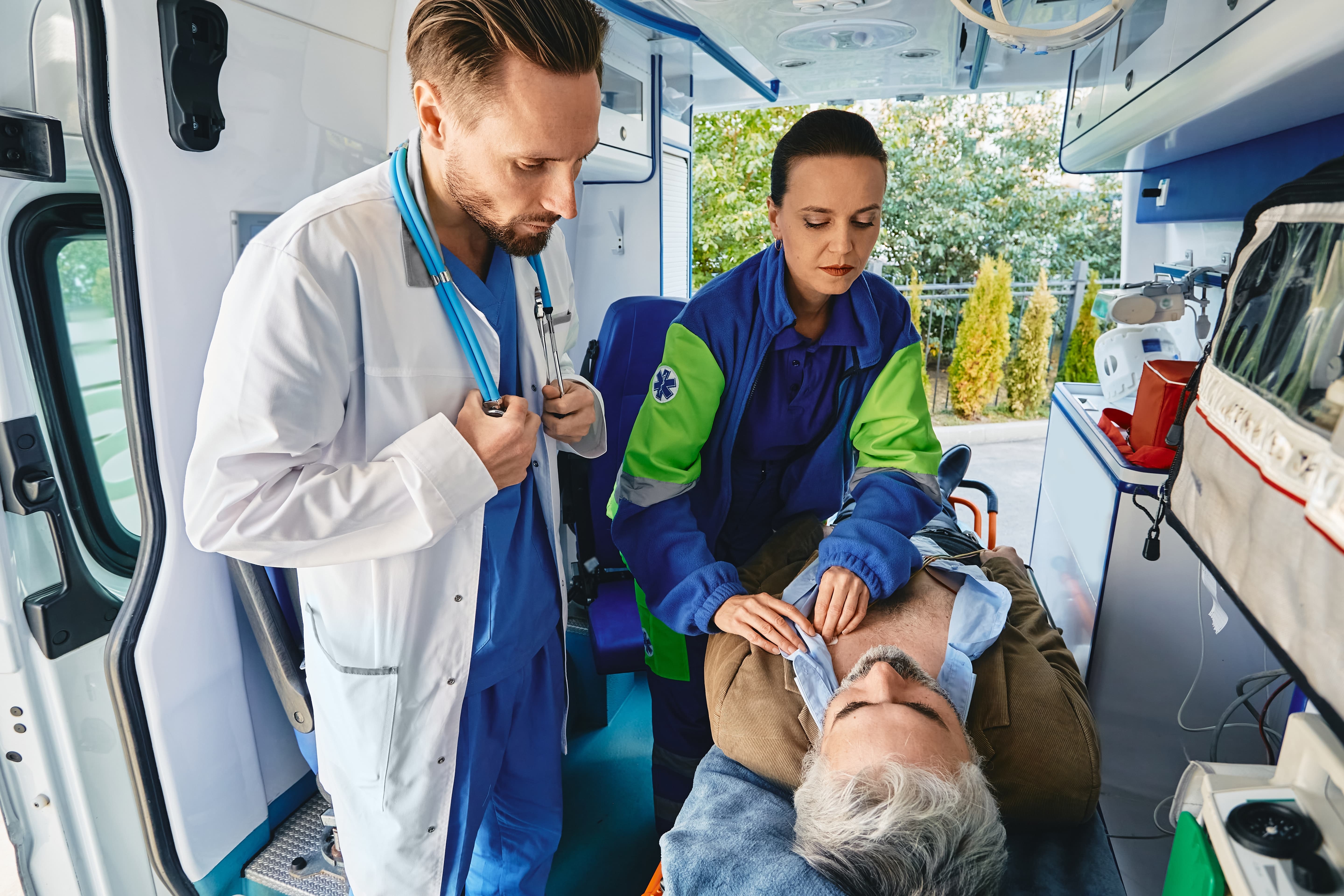 EMS professionals stabilizing a senior man in the ambulance